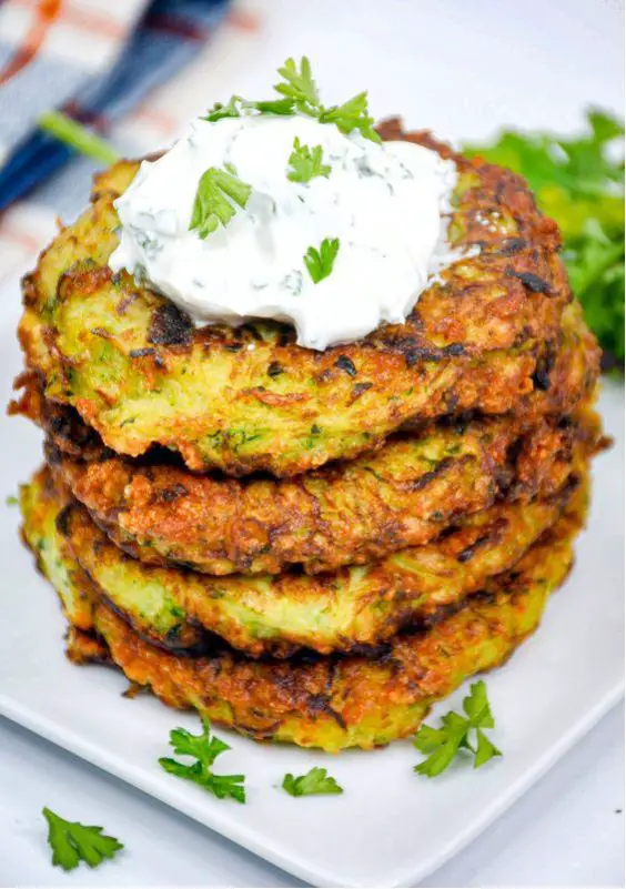 Golden crispy zucchini fritters on a white plate